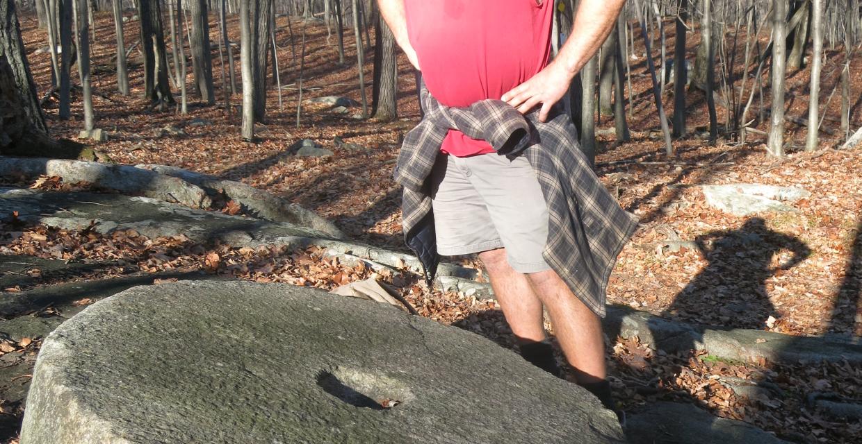 A hiker at a millstone at Camp Glen Gray.  Photo by Daniel Chazin.
